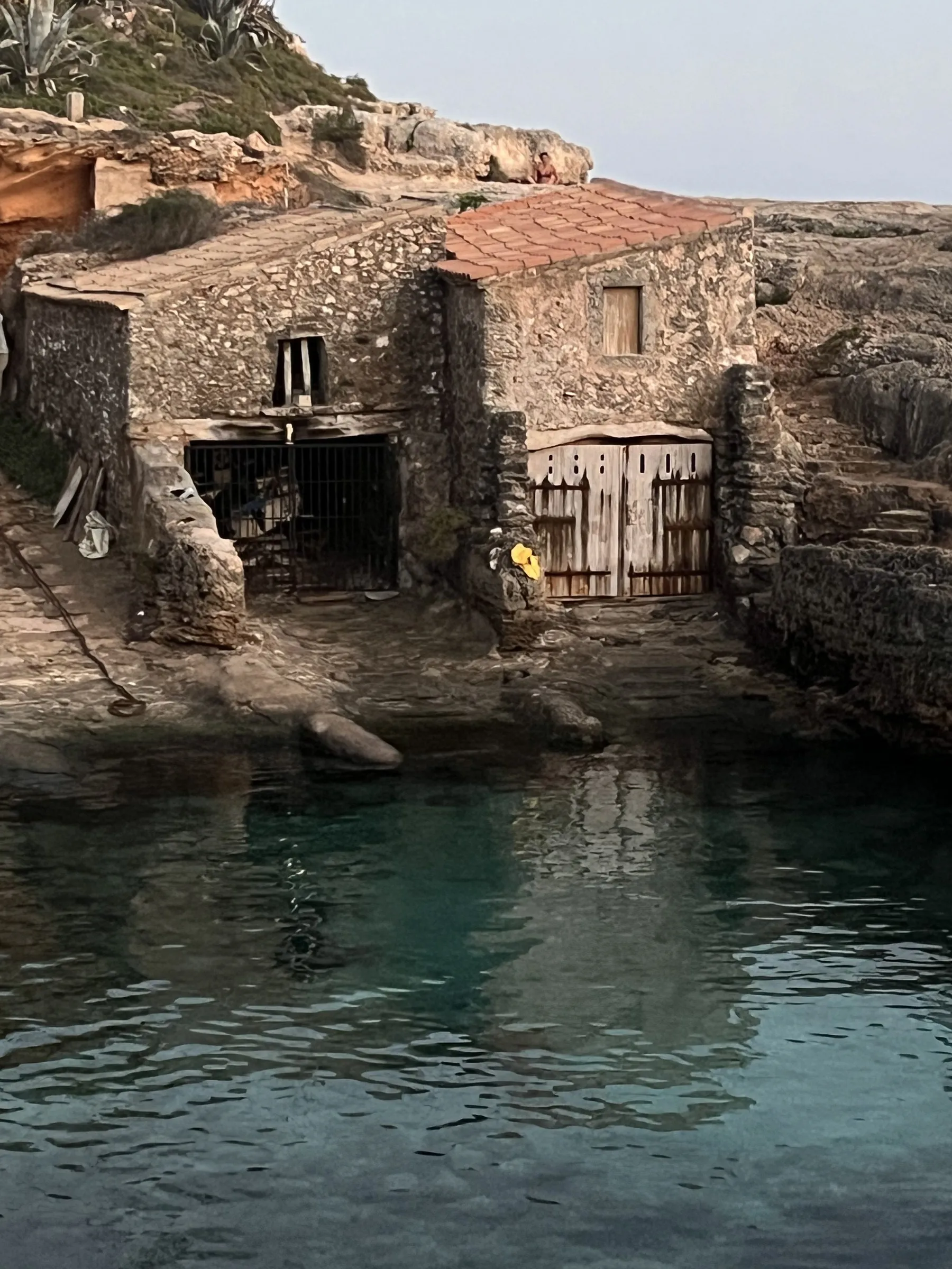 Un escar de piedra con la puerta de madera y el tejado de teja, construido sobre la roca justo encima del agua.